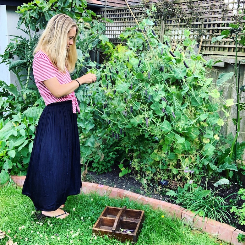 Lucy debout dans le jardin avec un haut à rayures roses