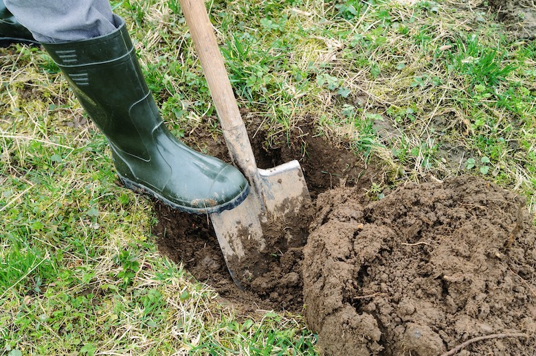 Plan rapproché de l'homme en bottes vertes creusant un trou dans le sol